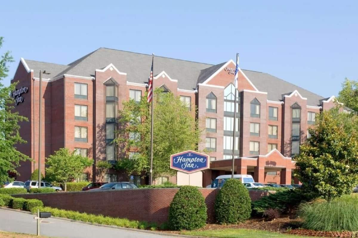 A Hampton Inn hotel with a brick facade, multiple windows, and a signboard.