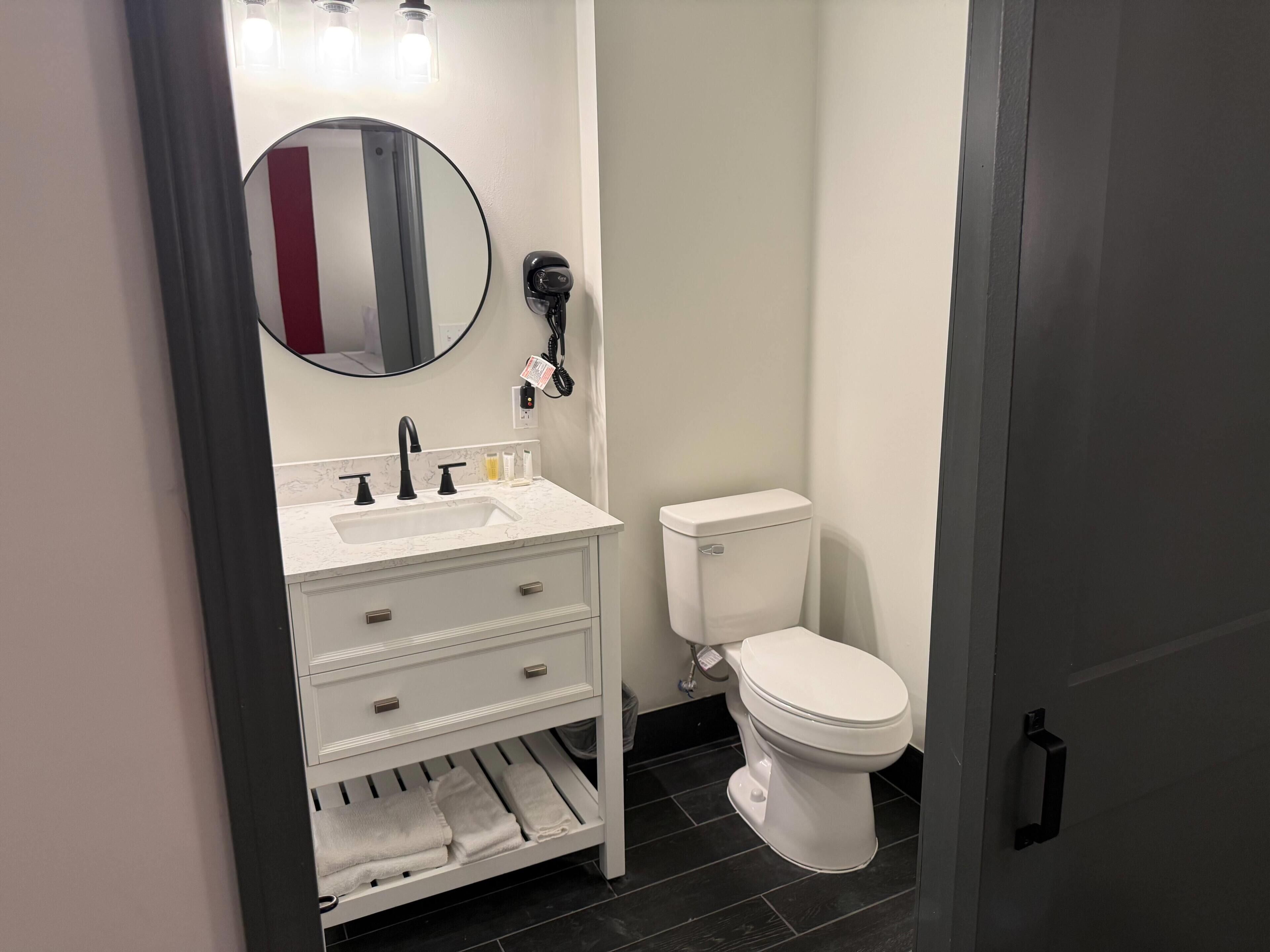 A modern bathroom with a white sink, mirror, and toilet.