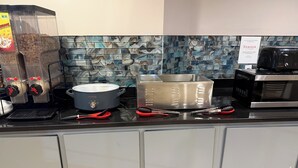 A kitchen with a coffee machine, a slow cooker, a pot, a toaster, and a microwave. - Ramada by Wyndham Albany GA (Albany)