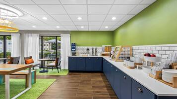 A modern kitchen with a green accent wall, white tiled backsplash, and wooden flooring.