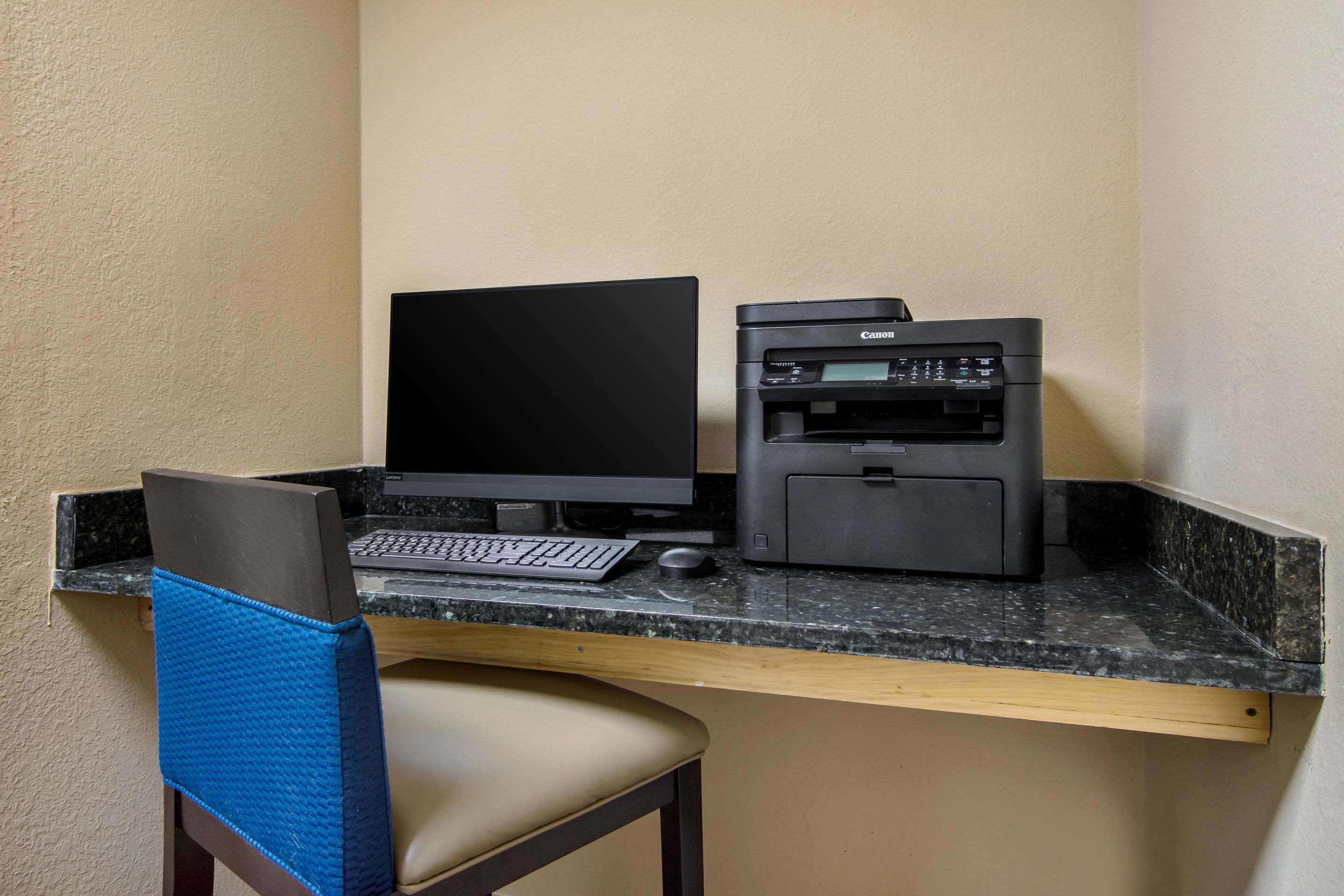 A workspace with a laptop, keyboard, mouse, and a Canon printer on a granite countertop.
