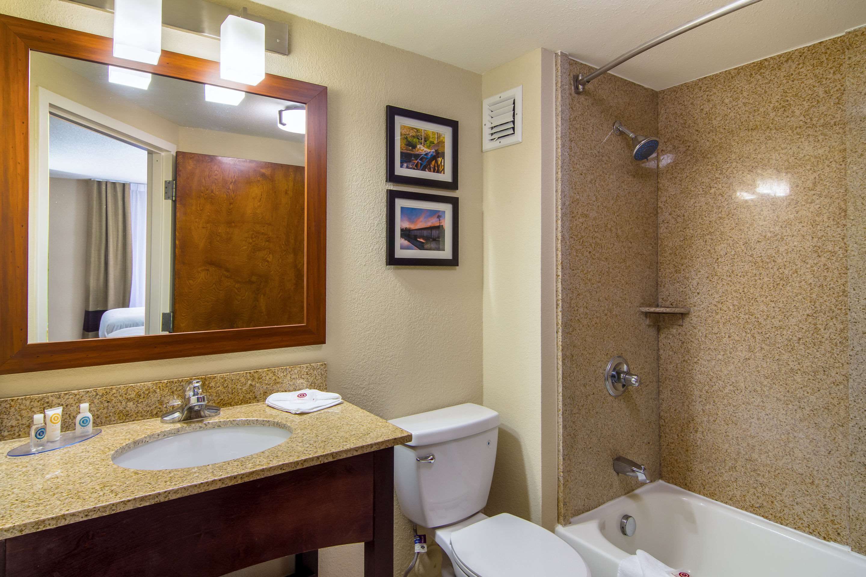 A bathroom with a sink, toilet, and bathtub. There are two framed pictures on the wall.