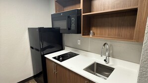A compact kitchen with a refrigerator, microwave, stove, and sink.