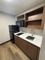 A compact kitchen with a refrigerator, microwave, stove, and sink.