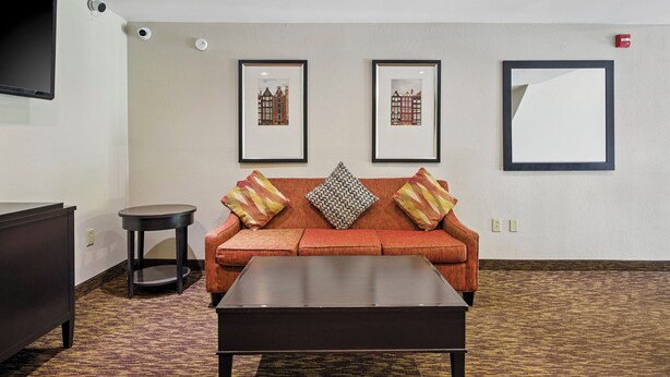 A hotel room with a sofa, a coffee table, a TV, and framed pictures on the wall.