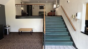 A staircase with a wooden handrail and a bench at the bottom.