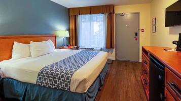 Una habitación de hotel con cama, escritorio, televisor, armario y una puerta.