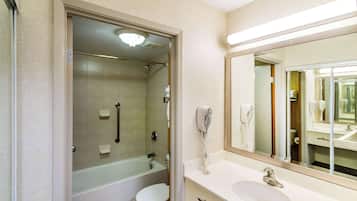 A bathroom with a glass-enclosed shower, a toilet, a sink, and a mirror.