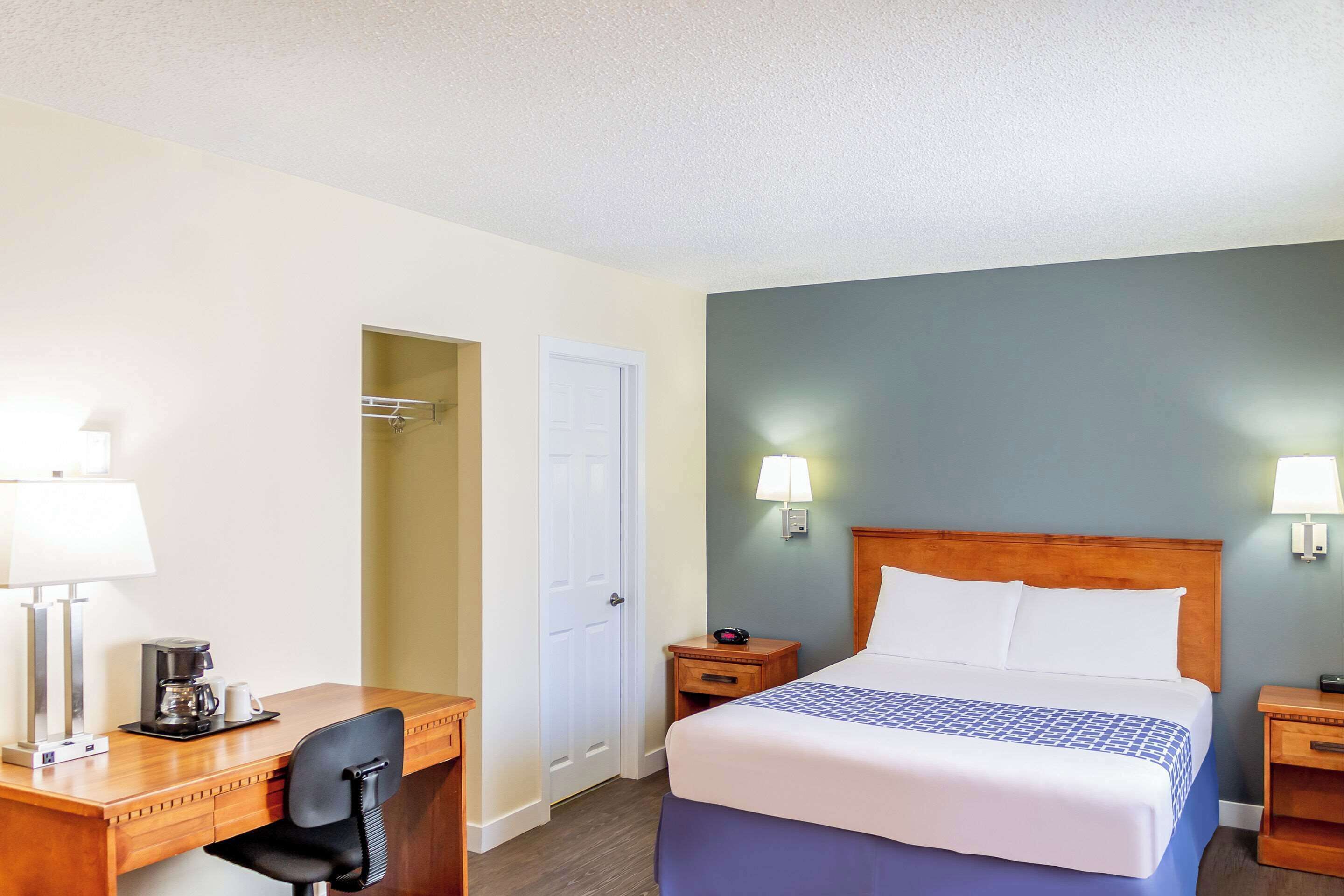 Una habitación de hotel con cama, escritorio, silla y dos mesitas de noche.