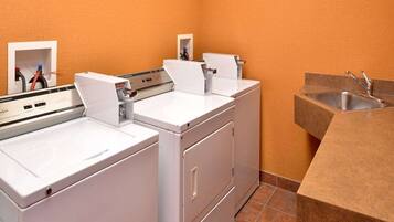 A laundry area with two white washing machines, a sink, and a towel rack.