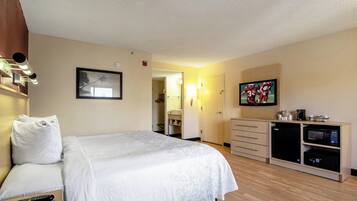 Une chambre d’hôtel équipée d’un lit, d’un bureau, d’une télévision et d’un mini-bar.