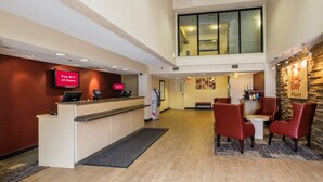 Un vestíbulo de hotel con una recepción, señal de Wi-Fi gratuito y un letrero de Red Roof Plus.