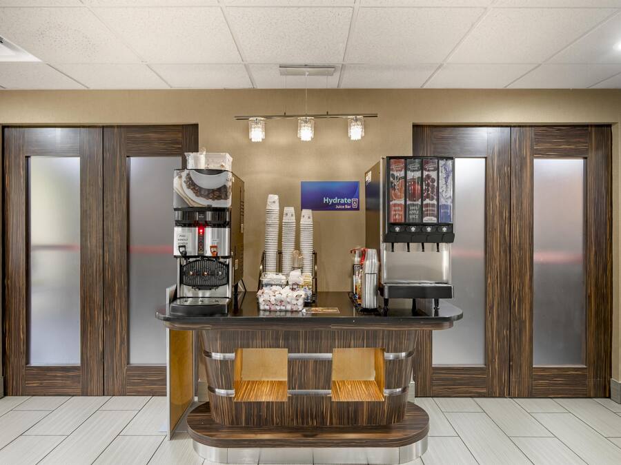 A hotel reception area with a coffee station, juice bar, and a counter with a sign for 'Hydrate Juice Bar'.