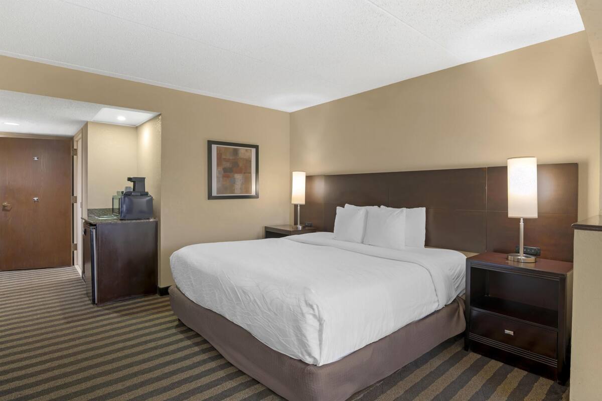 Een hotelkamer met een groot bed, twee nachtkastjes, een bureau en een stoel.