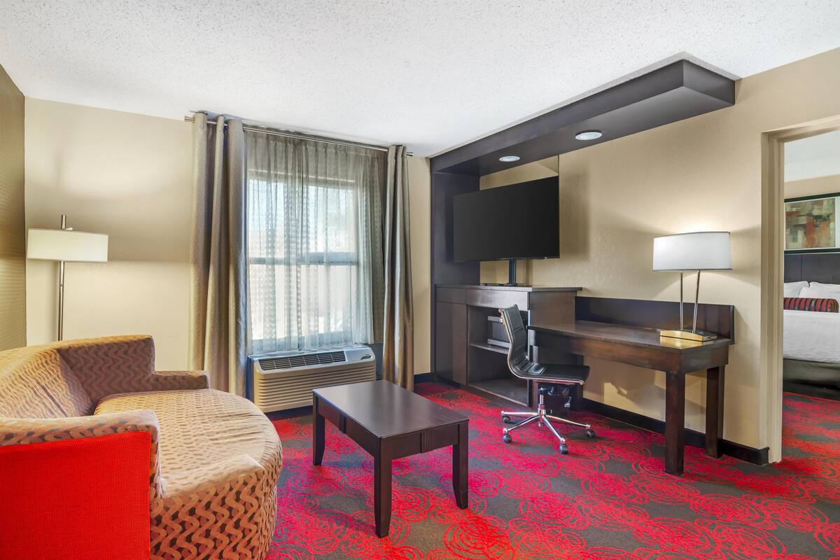 Een hotelkamer met een bank, bureau, stoel, televisie en bed.