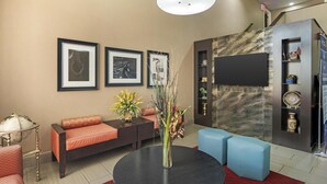 Una sala de estar moderna con un sofá, una mesa redonda con un florero y un televisor montado en la pared.