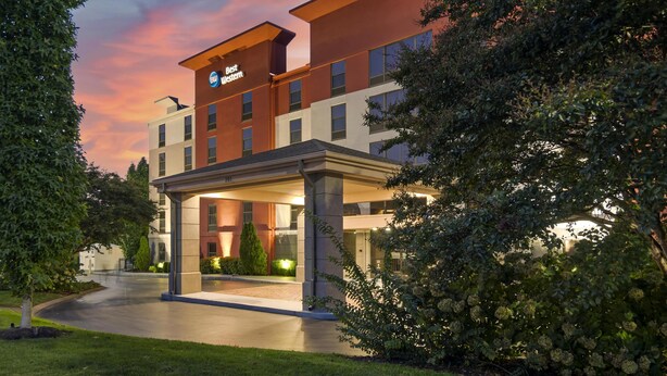 Un hotel con un diseño arquitectónico moderno, que cuenta con una entrada destacada con un corredor cubierto y un letrero que dice "Best Western".