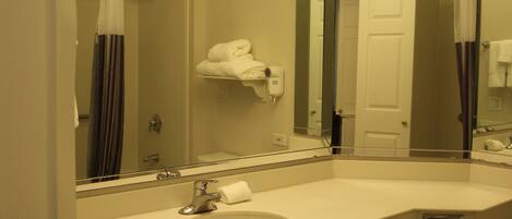 A bathroom with a large mirror, a sink, a towel rack, and a shower curtain.