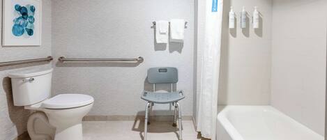 Baño con inodoro, ducha y barra de apoyo.