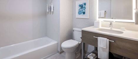 A modern bathroom with a bathtub, toilet, and vanity with a mirror.