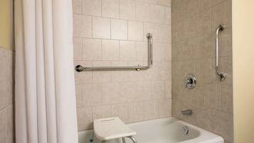 A bathroom with a shower, grab bars, and a small step stool.