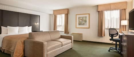 Una habitación de hotel con cama, sofá, escritorio y silla, y televisión.