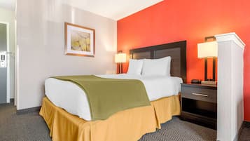 Quarto de hotel com uma cama, mesas de cabeceira, abajur e um quadro na parede.
