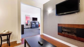 A modern living room with a flat-screen TV mounted on the wall, a fireplace, and a remote control on a coffee table.