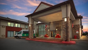 A hotel with a covered entrance, stone pillars, and a van parked outside.