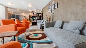 A modern living room with orange and grey sofas, a coffee table, and a bookshelf.