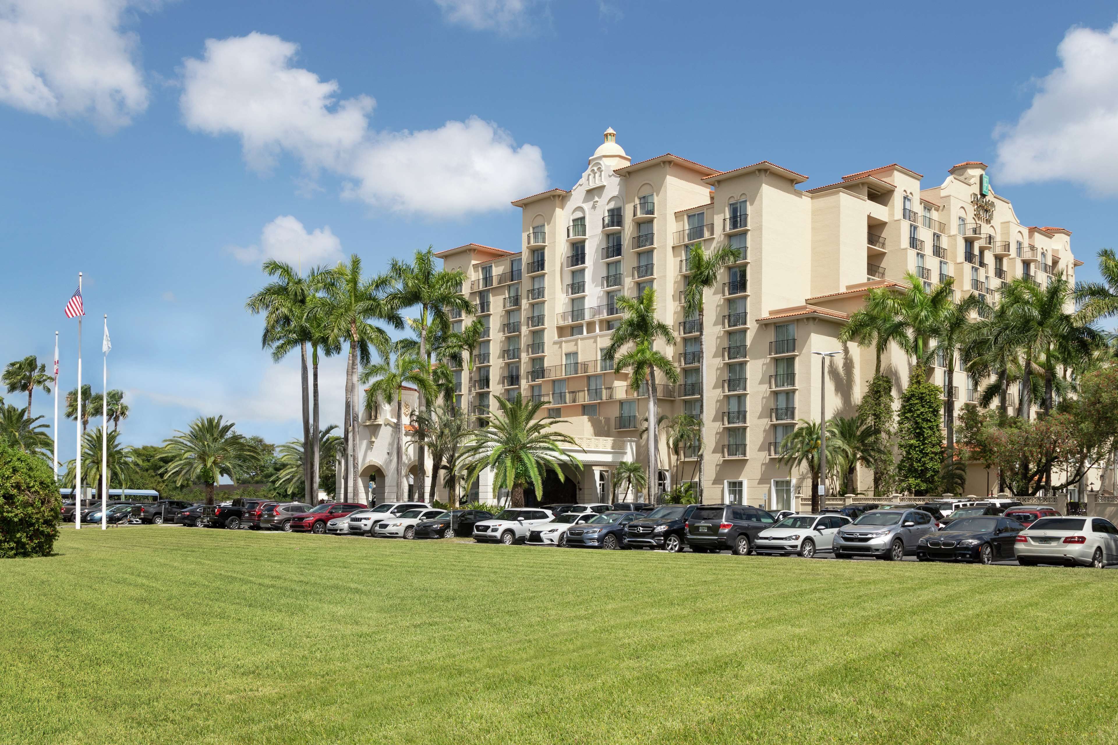 A hotel with multiple floors, palm trees, and a parking lot.