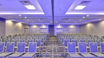 A conference room with rows of chairs, a carpeted floor, and a ceiling with recessed lighting.