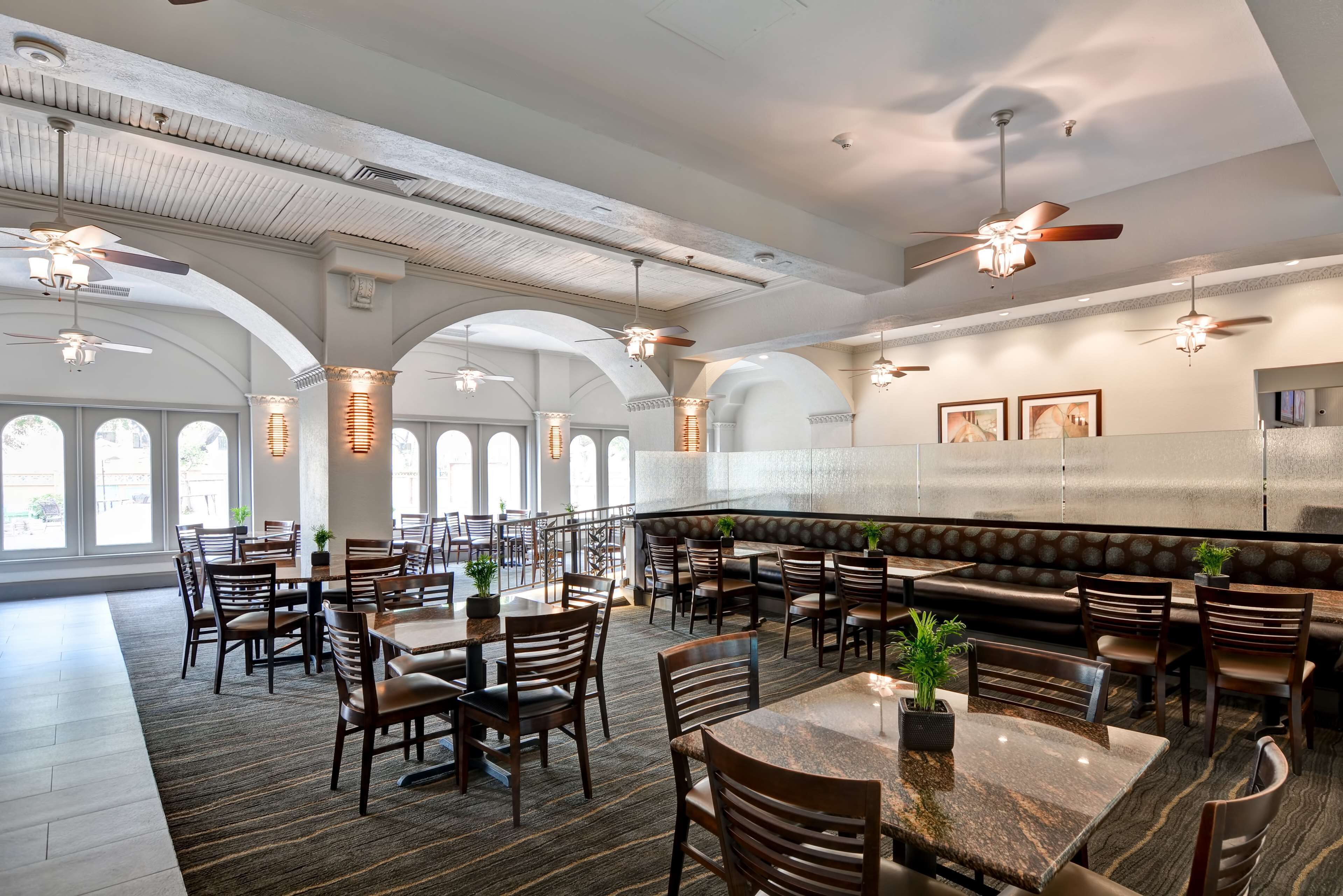 A spacious restaurant with high ceilings, arched windows, and multiple seating areas including tables and booths.