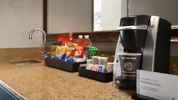 En hotellreception med en kaffebryggare, en skylt som visar vägen till de lyxigaste sviterna, samt ett urval av snacks och drycker.