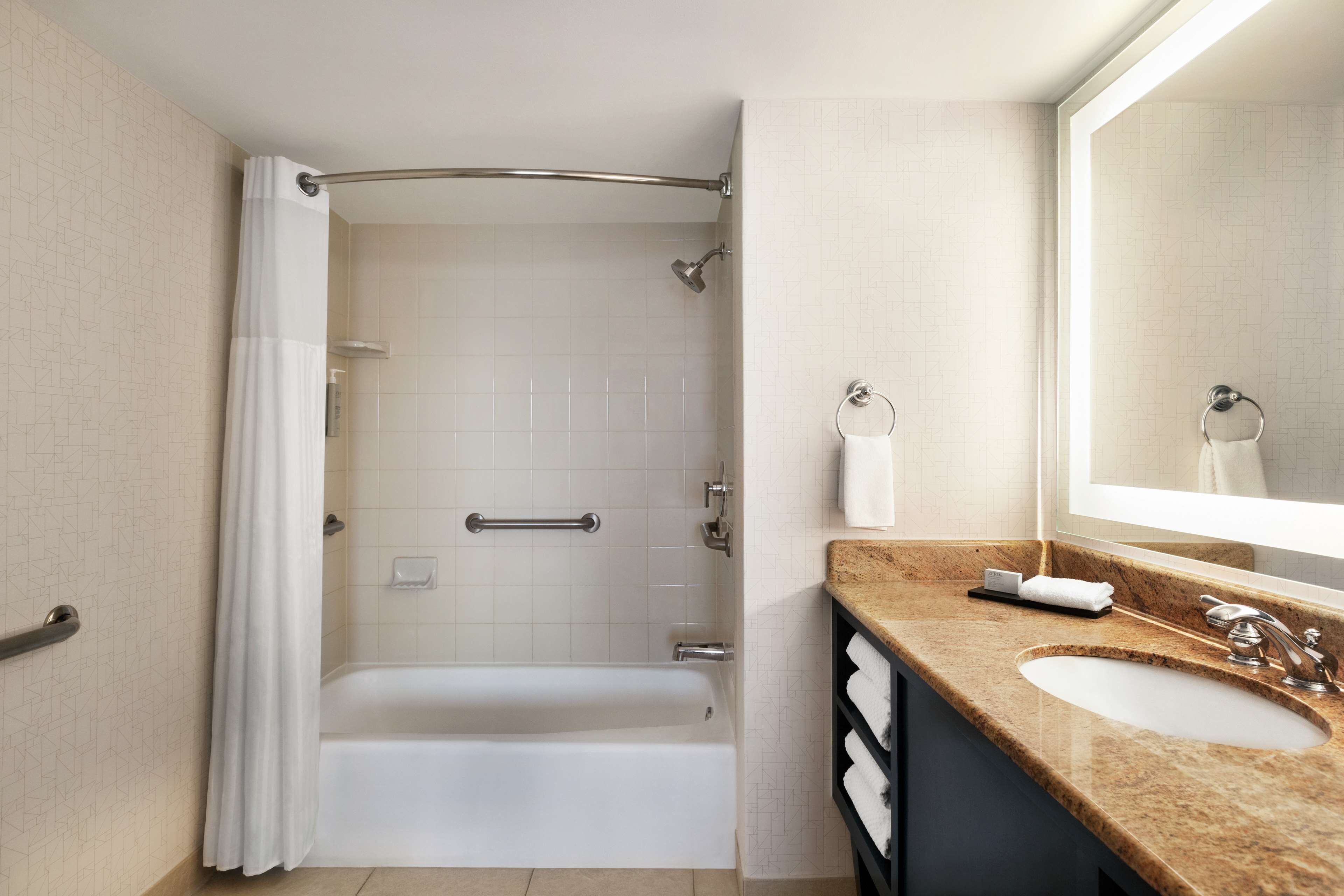 A modern bathroom with a bathtub, a vanity with a sink, and a large mirror.