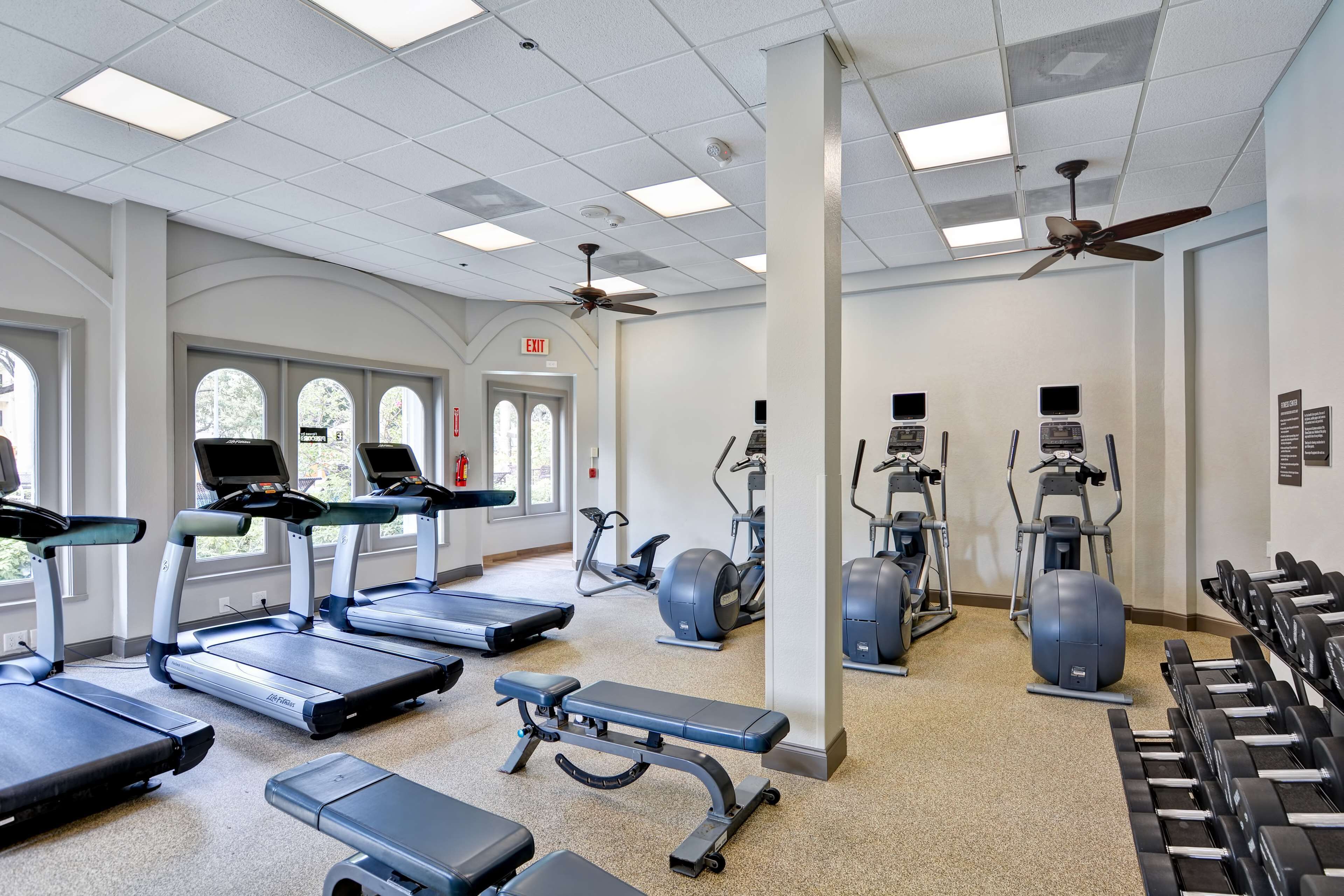 Ein Fitnessstudio mit Laufbändern, Crosstrainern und Kurzhanteln.