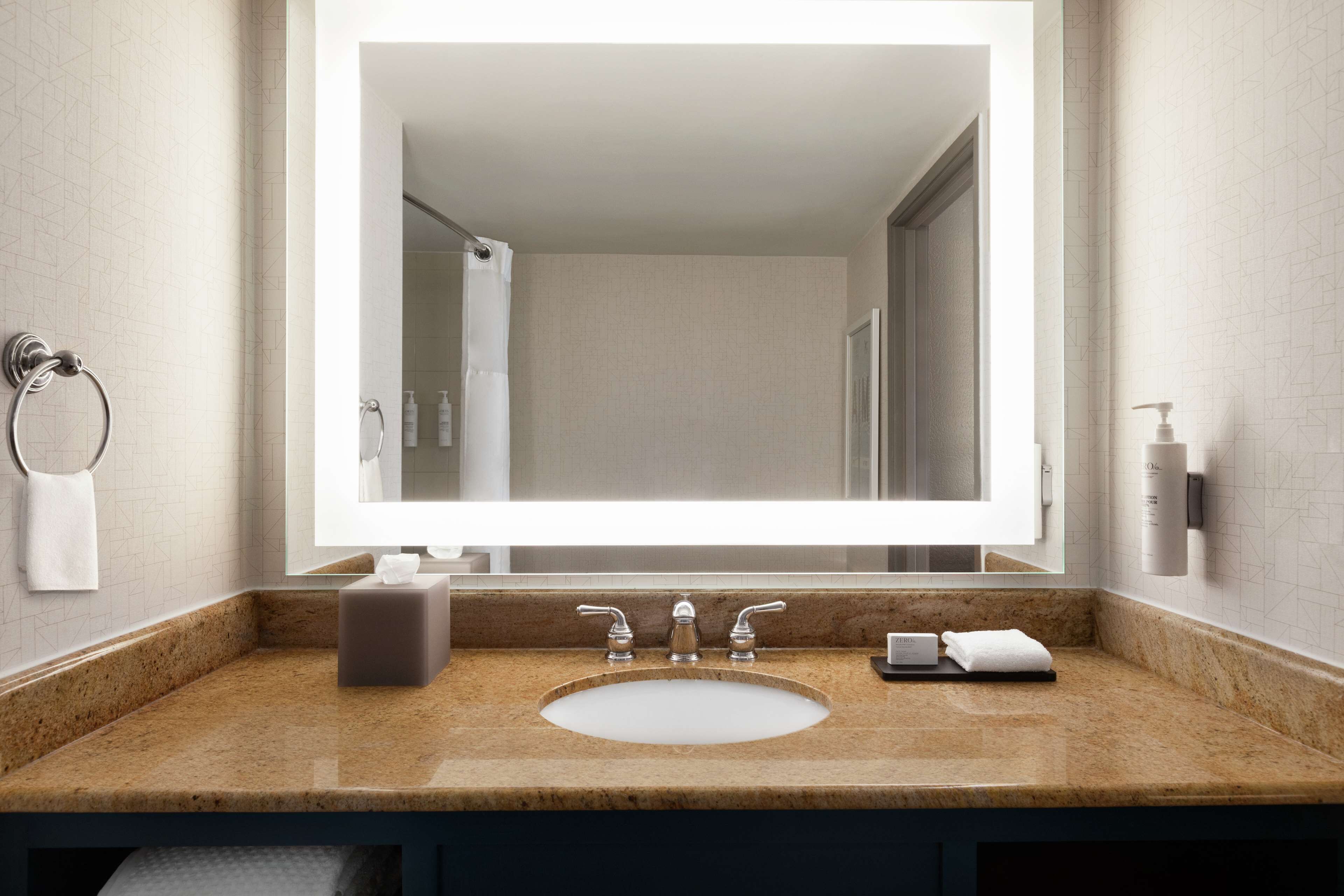 Un bagno con un ampio specchio, un lavandino e un portasciugamani.