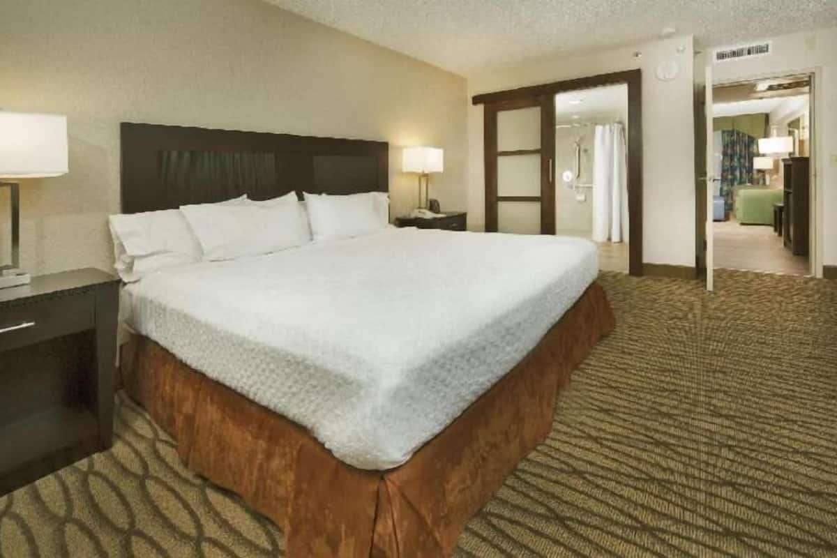 Una habitación de hotel con una cama grande, una mesita de noche, una lámpara y un armario.