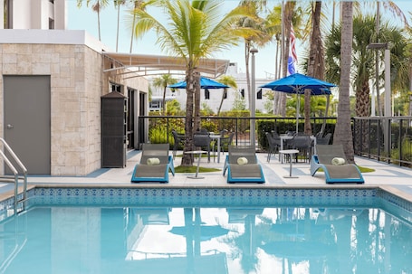 Una piscina al aire libre, sombrillas, sillones reclinables de piscina