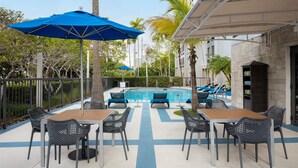 Un espace aménagé au bord de la piscine, comprenant une piscine, des chaises longues et des parasols.
