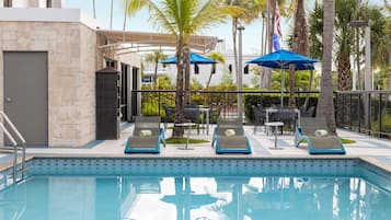 Una piscina al aire libre, sombrillas, tumbonas