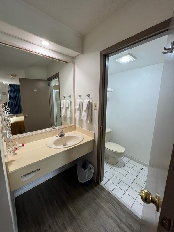 Un baño moderno con un lavamanos color beige, un espejo grande y un inodoro.