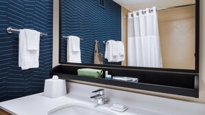 Un baño moderno con un espejo grande, lavamanos blanco y barra para toallas.