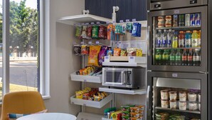 A vending machine area with snacks, drinks, and a microwave. - Spark by Hilton Brockville (Brockville)
