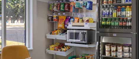 A vending machine area with snacks, drinks, and a microwave.