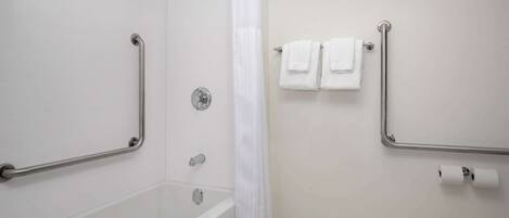 A bathroom with a bathtub, a shower with a grab bar, a white shower curtain, and two towels on a towel rack.