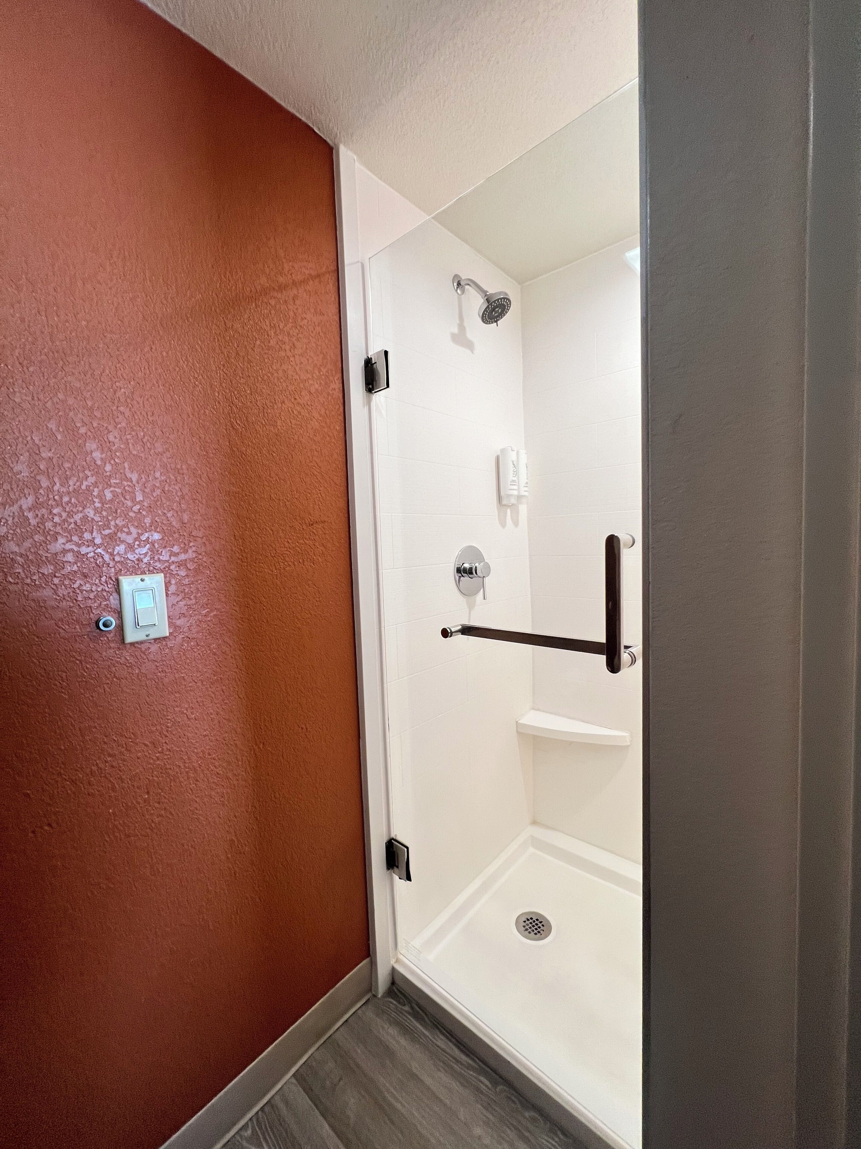 A bathroom with a shower, a towel rack, and a toilet.