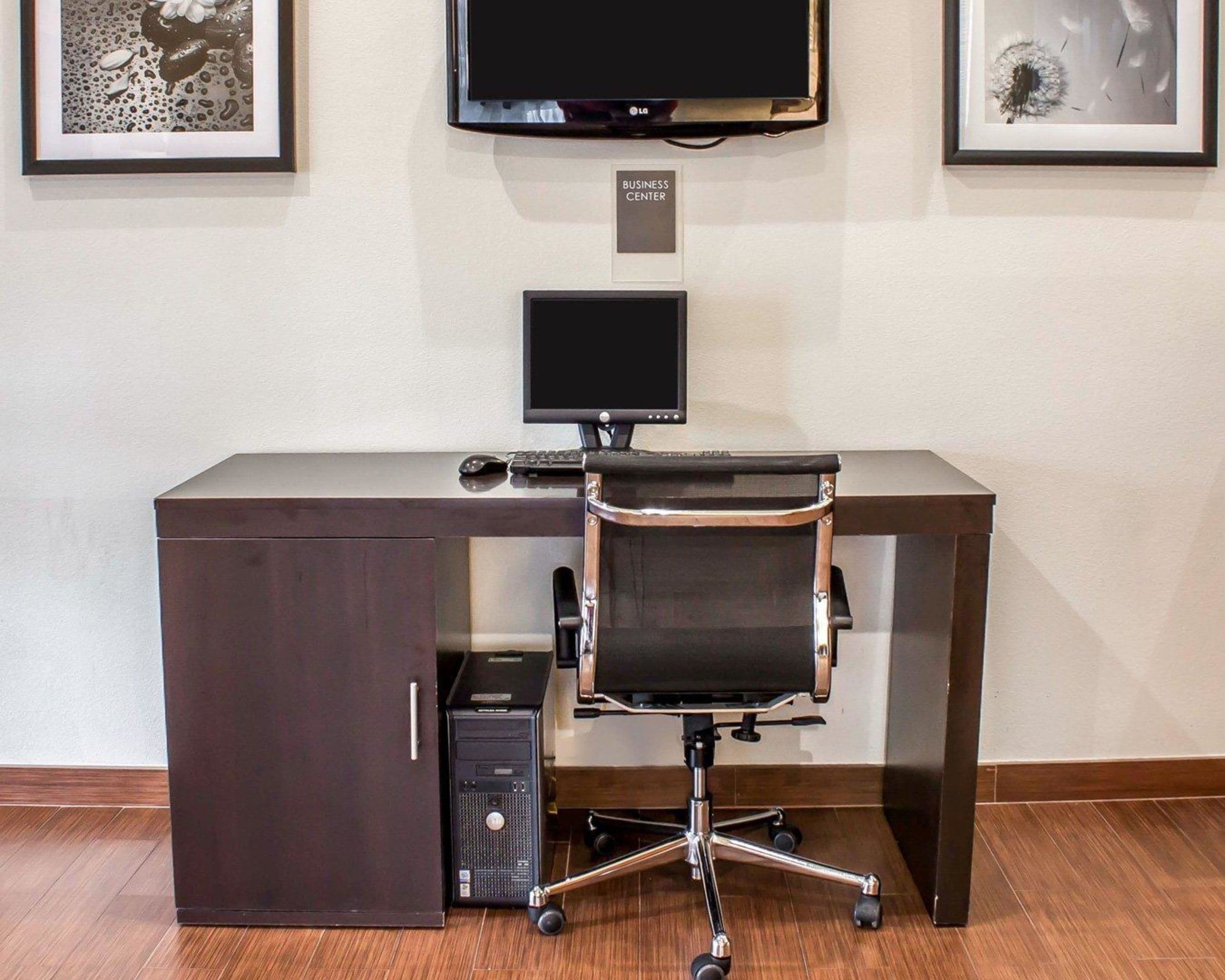 A modern office desk with a computer, a chair, and a monitor.