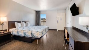 A hotel room with a bed, bedside table, desk, chair, and a TV mounted on the wall. - Motel 6 Tucson, AZ (Tucson)