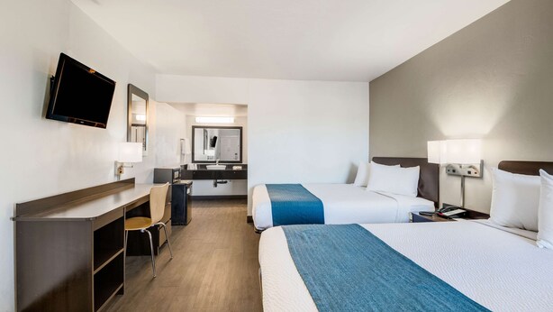 A hotel room with two beds, a desk, a chair, a TV, and a bathroom visible in the background. - Motel 6 Tucson, AZ (Tucson)